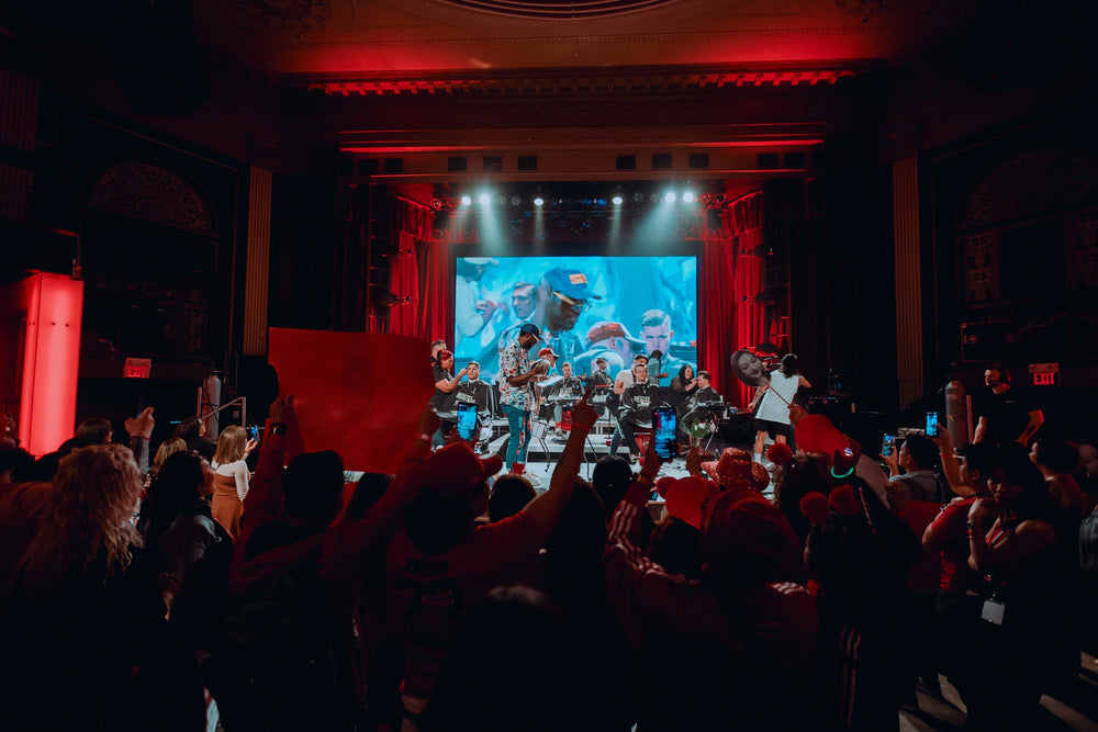 Photo at a Tommy Gun's event with barbers on stage cuting hair with a crowd spectating.